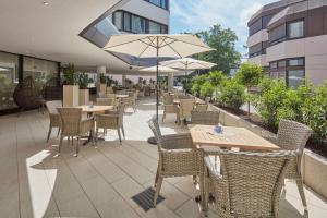 an outdoor patio with tables and chairs and an umbrella at Best Western Hotel Trier City in Trier