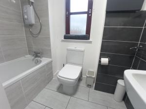 a bathroom with a toilet and a tub and a sink at Steam Train Cottage in Aviemore +14 photos
