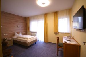 a bedroom with a bed and a desk and a tv at Hotel Weidenau in Bad Orb