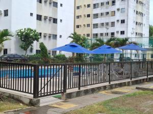 a black fence with blue umbrellas and a pool at Apartamento completo,no Janga, perto de Olinda in Paulista +6 photos