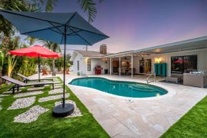 a swimming pool with an umbrella and a house at Heated Pool Mini Golf Game Room Near Beaches in Bradenton