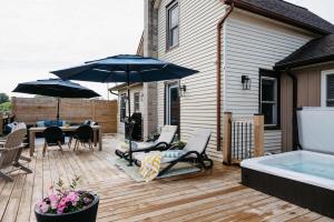 a patio with a hot tub and chairs and an umbrella at Park and Mill - Hot Tub and Bocce Court in Bloomfield