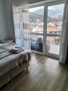 a bedroom with a bed and a large window at Tutu Studio Sinaia cu vedere panoramica Early Checkin in Sinaia +23 photos