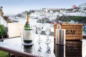 a bottle of champagne and two wine glasses on a table at High Hopes, Harbour Location with Sea Views in Brixham