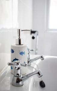 a bathroom sink with a faucet and a bottle of soap at High Hopes, Harbour Location with Sea Views in Brixham +35 photos