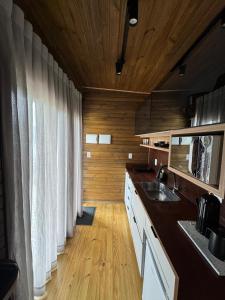 a kitchen with a sink and wooden walls and wooden floors at Refúgio Paraíso Casa Bela Vitta Spa externo in Orleans