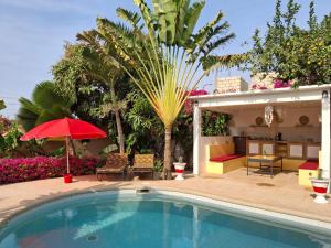 a swimming pool with a red umbrella and a house at Villa No Stress in Somone