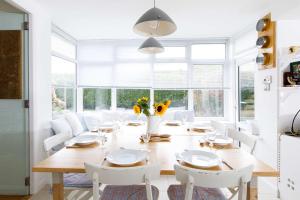 a dining room with a wooden table and white chairs at Secluded rural retreat close to beach - sleeps 12 in Earnley