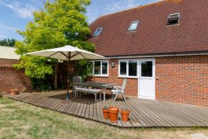a wooden deck with a table and an umbrella at Secluded rural retreat close to beach - sleeps 12 in Earnley