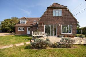 a house with a table and a bench in the yard at Secluded rural retreat close to beach - sleeps 12 in Earnley