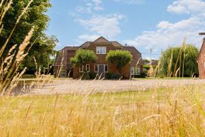 a house with a field in front of it at Secluded rural retreat close to beach - sleeps 12 in Earnley