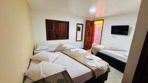 a hotel room with two beds and a tv at Pousada Cordel de Itaúnas in Itaúnas
