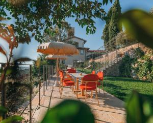 a table with orange chairs and an umbrella at La Monastica Resort & Spa in Borgo a Buggiano