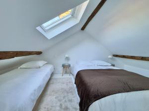 two beds in a white room with a window at Duplex - 5 min Insead - Close to Forest and Castle in Fontainebleau