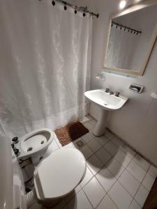 a white bathroom with a toilet and a sink at Retoño Serrano in Tandil