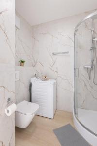 a white bathroom with a toilet and a shower at SuperApart Modern Stay Ursynów Pileckiego - Parking w cenie in Warsaw