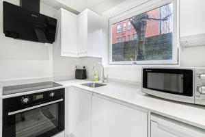 een witte keuken met een magnetron en een spoelbak bij Security House in Londen