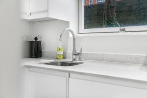 een witte keuken met een wastafel en een raam bij Security House in Londen +17 foto's