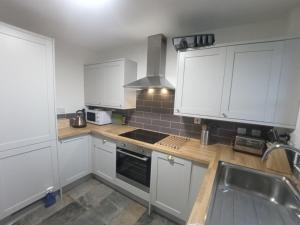 a kitchen with white cabinets and a sink at Steam Train Cottage in Aviemore