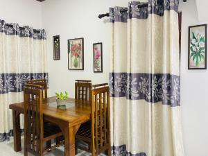 a dining room with a table and chairs and curtains at Kavi Villa in Weligama