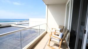 a balcony with a chair and a view of the ocean at Jolla Excellence 3bd 2b Rosarito in Popotla