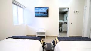 two beds in a white room with a picture on the wall at Jolla Excellence 3bd 2b Rosarito in Popotla