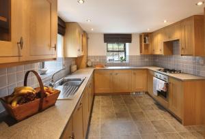 eine Küche mit Holzschränken und einem Obstkorb auf der Theke in der Unterkunft Damson Cottage in Rainow