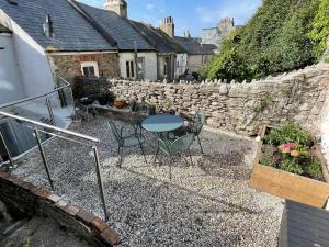 a patio with a table and chairs and a stone wall at Oyster Catcher Cottage - Harbour Bowl, Sea Views in Brixham