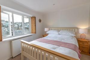 a bedroom with a white bed and two windows at Oyster Catcher Cottage - Harbour Bowl, Sea Views in Brixham +45 photos