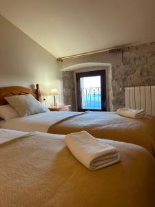 two beds in a bedroom with towels on them at Santuari Mare de Déu Del Mont Restaurant-Hostatgería in Beuda