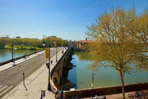 a bridge over a river next to a road at Hôtel des Beaux-Arts Toulouse in Toulouse