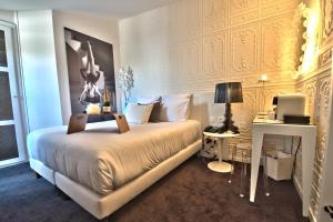 a bedroom with a king sized bed and a desk at Hôtel des Beaux-Arts Toulouse in Toulouse