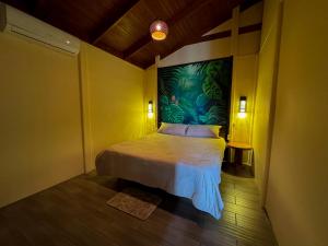 a bedroom with a bed with a painting on the wall at Villa Lomas Sarapiquí in Colonia Carvajal