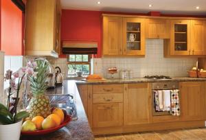 eine Küche mit Holzschränken und einer Schale Obst in der Unterkunft Orchard Cottage Cheshire in Rainow