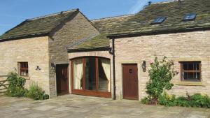 ein Backsteinhaus mit einer großen Glastür in der Unterkunft Orchard Cottage Cheshire in Rainow + 1 Foto