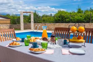 a table with food on it next to a pool at Villa La Vita in Čabrunići