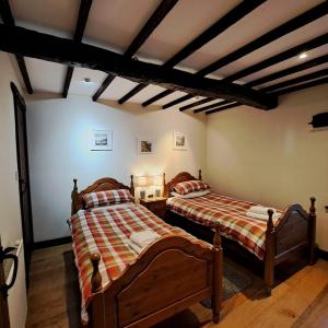 due letti in una stanza con soffitti in legno di Oakside Cottage Braithwaite a Braithwaite