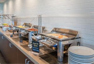 a buffet line with trays of food in a restaurant at Staybridge Suites Oxnard - River Ridge by IHG in Oxnard