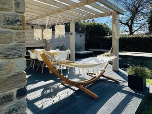 a patio with a table and a hammock on a deck at Dreamwood Cottage in Wakefield