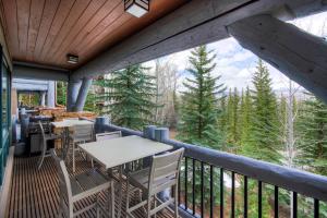 a deck with tables and chairs and a view of the forest at Bachelor Gulch Village by Vail Resorts in Avon