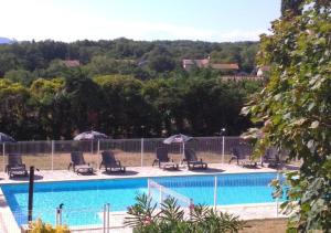 a pool with chairs and umbrellas next to a fence at Hotel Les Voyageurs - Vogüé in Vogüé