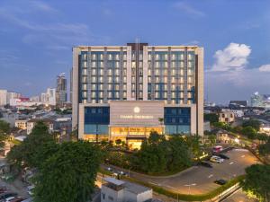 a large building with a sign on it in a city at Grand Orchardz Hotel Kemayoran Jakarta in Jakarta