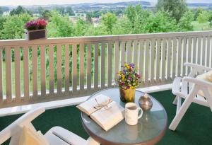 a table with a book and flowers on a balcony at Best Western Aparthotel Birnbachhöhe in Bad Birnbach