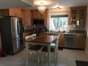 a kitchen with a table and a stainless steel refrigerator at Simcoe B&B - Incredible vacation suite in Smithers