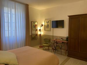 a bedroom with a bed and a desk and a television at L'Altro Sapore Rooms in Pitigliano