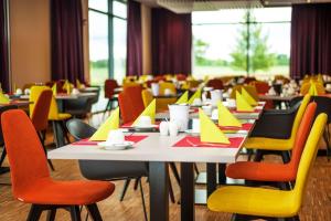 a dining room with tables and chairs with yellow chairs at BEST WESTERN Hotel The K Unterföhring in Munich +21 photos