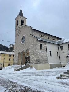 un grande edificio in mattoni con una torre dell'orologio nella neve di Casa Vacanza Piccolo Chalet a Roccaraso