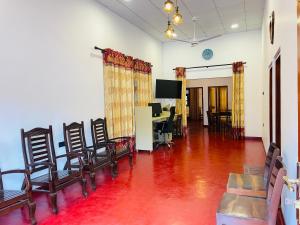a room with chairs and a table and a television at Serandib Beach Villa in Weligama