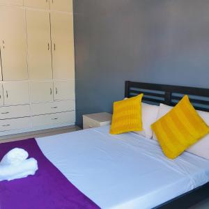 a bedroom with a bed with yellow and purple pillows at Home near Mt Gulugod Baboy in Batangas City +10 photos