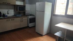 eine Küche mit einem weißen Kühlschrank und einem Herd in der Unterkunft Kitnet geminada próximo da praia in Torres